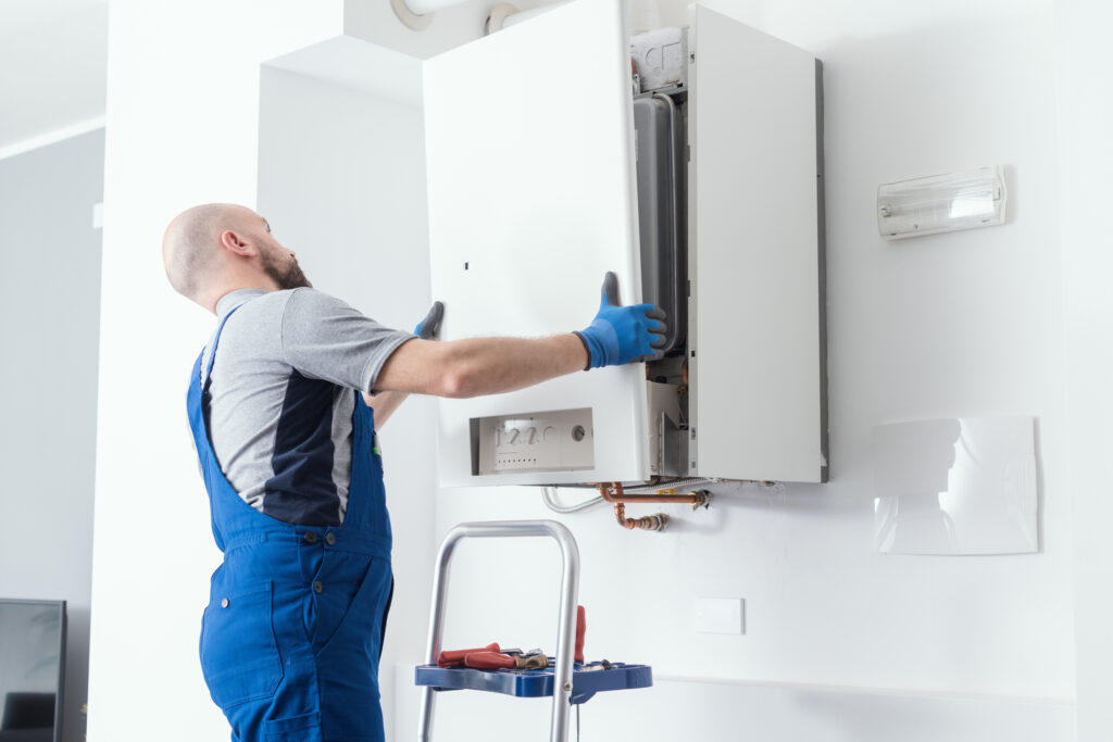 Technician installing boiler onto wall of home.
